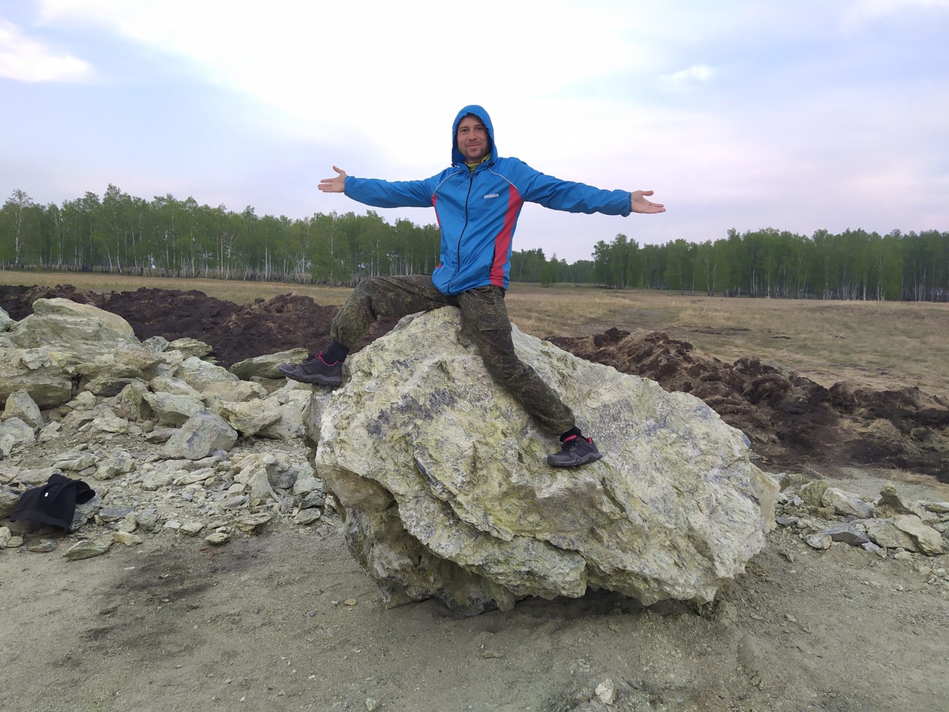 Мужчина в синей куртке на большом камне